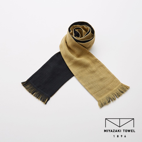 今治匹馬棉雙色圍巾，一端為黑色，另一端為卡其色，兩端皆有流蘇。