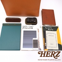 日本HERZ職人手作皮革公事包，搭配相機、平板、手機、筆記本等，展示商務與日常配件。