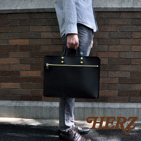 黑色皮革兩用公事包，配有金色拉鍊和铆釘。