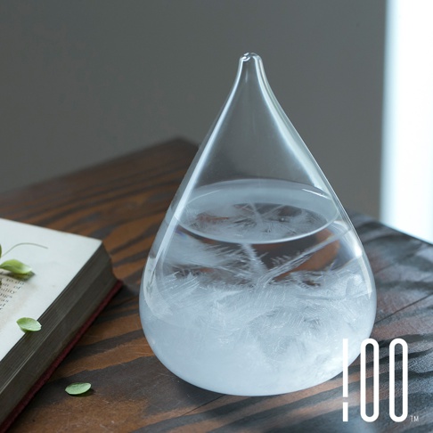 一個透明的玻璃製成，水滴狀的Tempo Drop天氣瓶，瓶內裝有液體，底部和中部有細緻的白色結晶，瓶口細長。