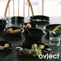 黑色琺瑯湯鍋組，包含多個湯鍋，盛裝著食物、檸檬塊與香草，搭配玻璃杯與餐具，擺放在餐桌上。