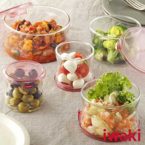 多個耐熱玻璃圓形微波保鮮盒，裝有蔬菜、水果、海鮮等食物，部分盒蓋為粉紅色。