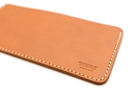 職人手作皮革紙鈔收納夾，淺棕色牛皮材質，車縫線清晰，右下角壓印「HERZ MADE IN JAPAN」字樣。