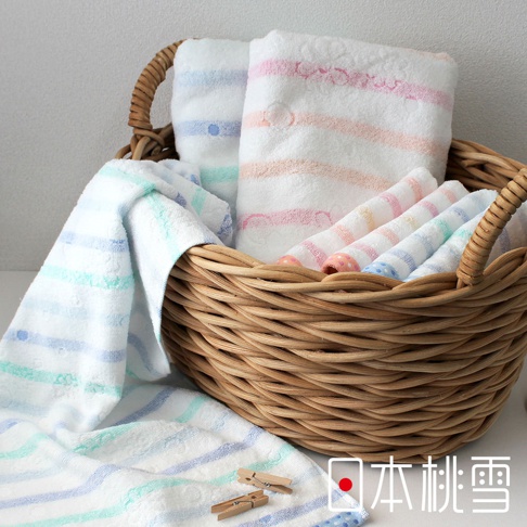 藤編籃子裡擺放著幾條今治小花毛巾，毛巾以白色為底，織有粉色、藍色、綠色和橘色的條紋，部分毛巾上可見小巧的花朵圖案。