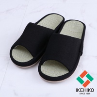 一雙黑色的藺草透氣室內拖鞋，鞋面為織物材質，鞋墊為藺草編織，呈現天然的淺綠色，拖鞋開口設計，適合居家穿著。