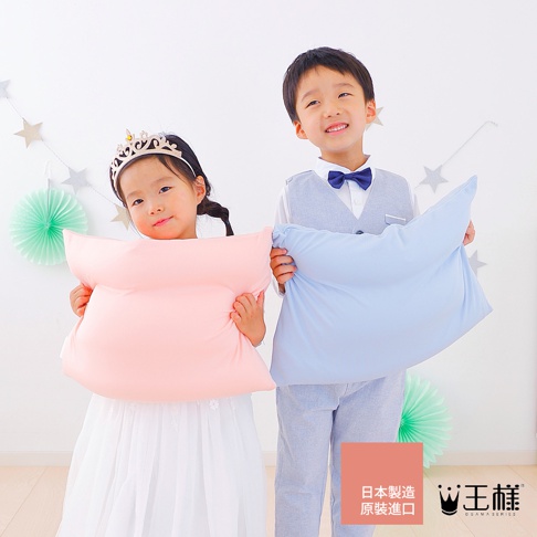 一對男女童分別抱著粉紅色和淺藍色軟枕，背景是白色牆壁，裝飾有綠色紙扇和銀色星星拉繩。