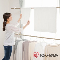 木紋頂天立地窗框曬衣架，展示架上方懸掛兩條白色毛巾，下方掛有數件不同顏色的衣物。