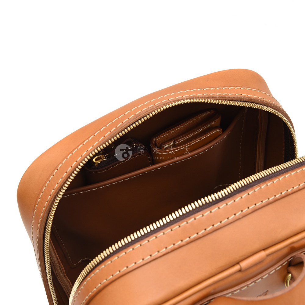 職人手作皮革長方型後背包，主體為淺棕色皮革，內部有拉鍊隔層及皮夾，縫線細緻，風格簡約。