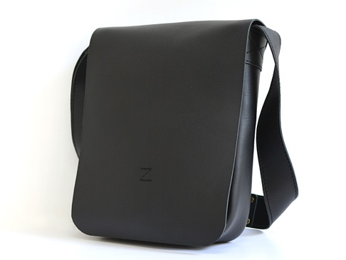 黑色皮革軟皮直式斜背包，帶有品牌壓印的「Z」字樣，以及可調節的肩帶。