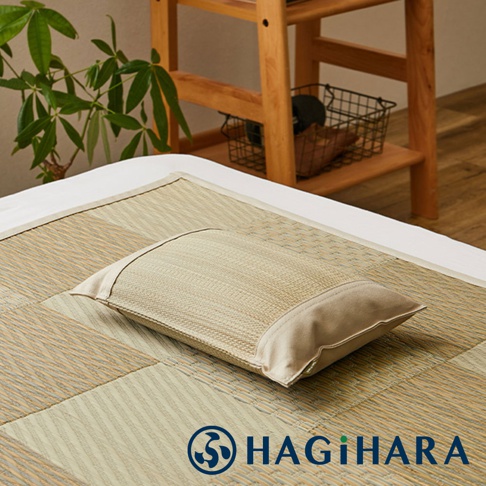 藺草調濕透氣舒眠枕，枕面為淺褐色藺草編織，枕套邊緣為米白色布料，擺放在同款淺褐色藺草編織的床墊上。