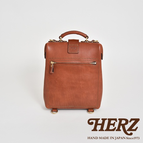 職人手作皮革迷你軟皮杜勒斯包，採用棕色皮革製成，配有金色拉鍊、頂部提把和兩個底部 D 型環。