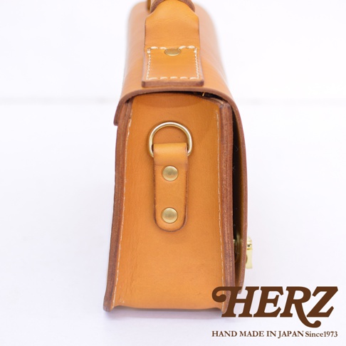 職人手作淺棕色皮革經典兩用迷你單肩包，側面特寫，露出金屬D型環、鉚釘及包蓋細節。