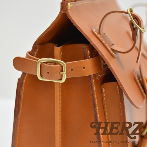 職人手作皮革旅行包 A-102，採用天然皮革材質，呈現溫潤的棕褐色調。包款細節包含黃銅釦環、縫線裝飾及皮革提把，展現簡約經典的設計風格。