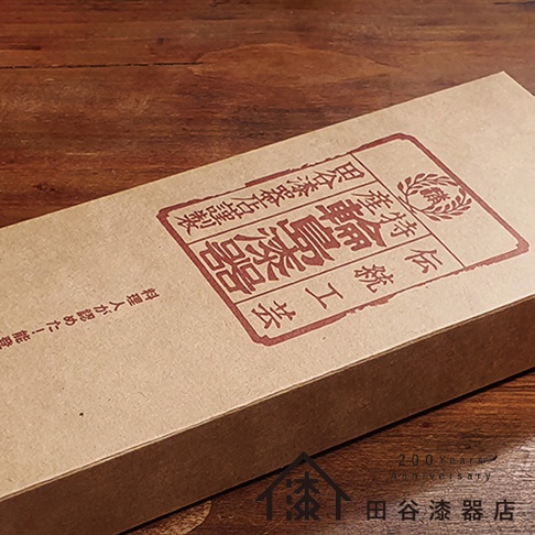 輪島塗漆能登檜料理鏟包裝盒，牛皮紙盒表面印有紅色日文文字與圖騰，字樣包含「輪島塗」與「能登檜」。