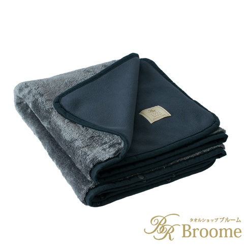 灰色毛絨保暖毯，一面為細緻的絨毛材質，另一面為深藍色平滑絨布，兩面皆有深藍色滾邊。毯子折疊起來，內側可見品牌標籤。