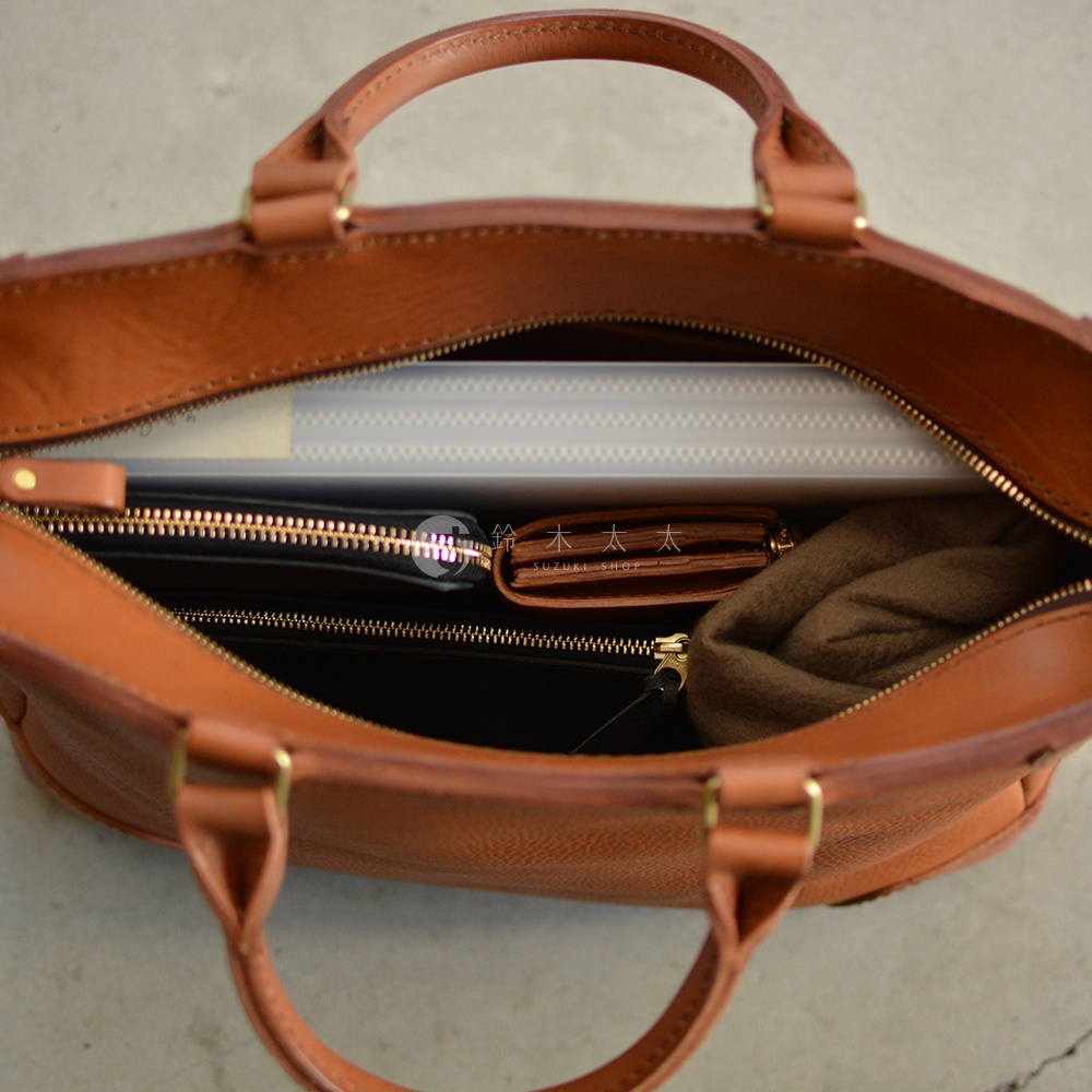 職人手作皮革Organ兩用商務托特包，採用棕色皮革材質，包內裝有文件夾、黑色長夾、短夾和咖啡色圍巾，展示其收納功能。