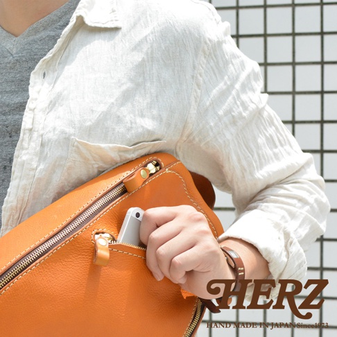 職人手作皮革多功能收納斜背包 F-3，展示為亮橘色皮革，包款擁有拉鍊主袋和前方拉鍊小袋，可放置手機。