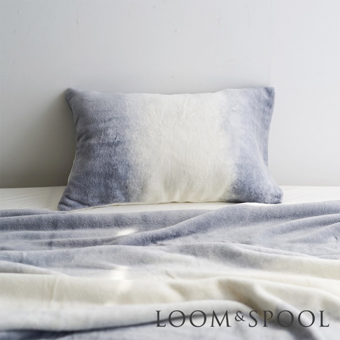 淺灰色與白色暈染的短絨舒柔枕套，材質柔軟，搭配同色系鋪展的短絨布料。