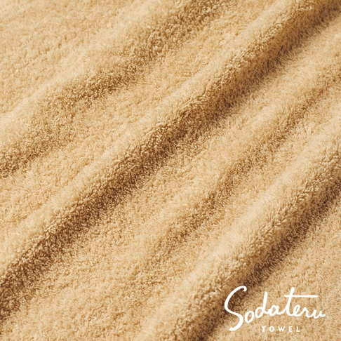 Sodateru TOWEL 品牌字樣於柔軟的淺棕色毛巾織物上。