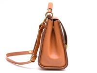 職人手作皮革屋瓦風兩用單肩包，採用棕褐色皮革製成，設有可調整的長肩帶和頂部提把，搭配金屬扣環，包身線條簡潔。