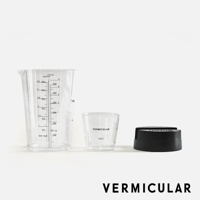 透明量杯、透明米杯，以及一個黑色鑄鐵鍋底座，均帶有 Vermicular 品牌標識。