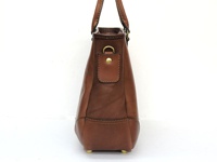 職人手作皮革兩用商務托特包，採用棕色光滑皮革製成，側面可見金屬扣環和縫線細節，包包底部配有四個金色金屬腳釘。