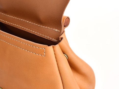 淺棕色皮革迷你後背包特寫，展示縫線細節與包口開啟處。