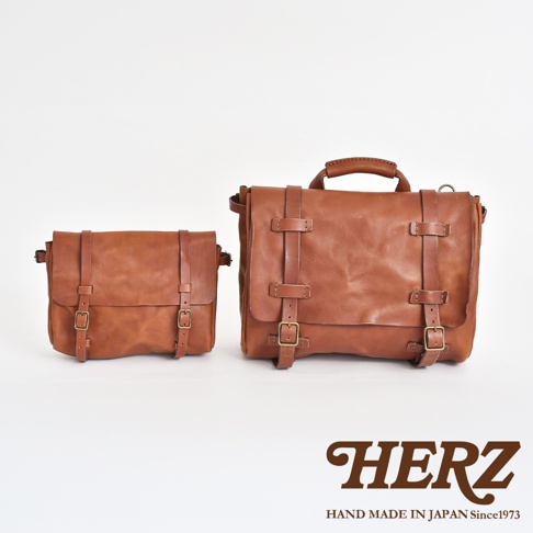 兩款棕色皮革復古郵差包，尺寸不同，皆有雙皮帶扣設計，其中較大款帶有提把。
