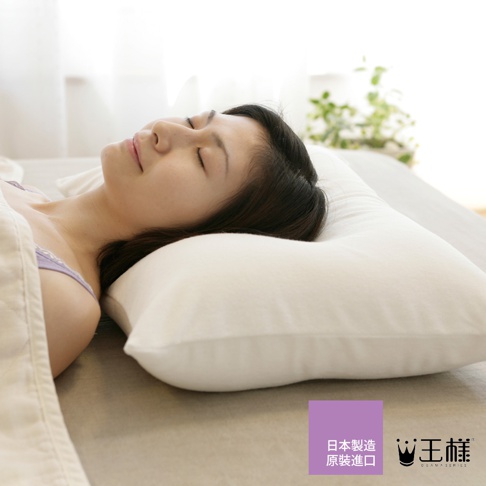 一位女性仰躺在柔軟的白色枕頭上，枕頭為「王樣の夢枕」產品，材質為絨毛，觸感舒適。