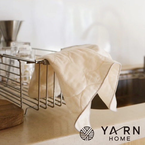 米白色菱格紋縫線廚房拭巾，材質為脫脂棉混紗，懸掛在金屬瀝水架上。