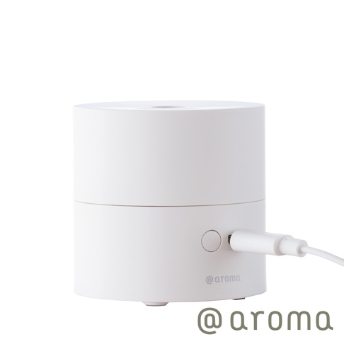 白色圓柱形隨身精油香氛機，頂部有出霧孔，側面有電源按鈕及USB充電孔，機身印有@aroma標誌，整體為光滑的塑膠或金屬材質。