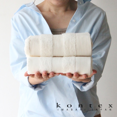 雙色今治雙織有機棉毛巾，以鬆餅紋織法呈現，質地柔軟，兩條毛巾疊放，由雙手捧持。