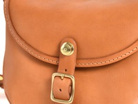 職人手作皮革休閒旅行馬鞍包 (CK-20)，採用天然皮革製成，呈現溫潤的棕褐色。包包的翻蓋處縫有細緻的白色縫線，並配有復古金屬釦環和銅色按釦，展現精緻的手工藝。