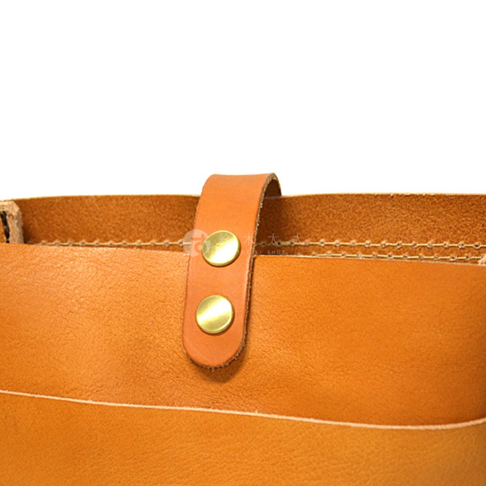 日本HERZ品牌職人手作皮革軟皮直式斜背包CK-98的細節，特寫橘棕色皮革斜背包的兩顆金色鈕扣和一條皮革固定帶。