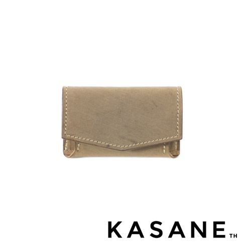 KASANE 品牌標誌下方有一個卡其色皮革迷你錢包，錢包頂部有一個斜切翻蓋，翻蓋周圍有縫線細節。