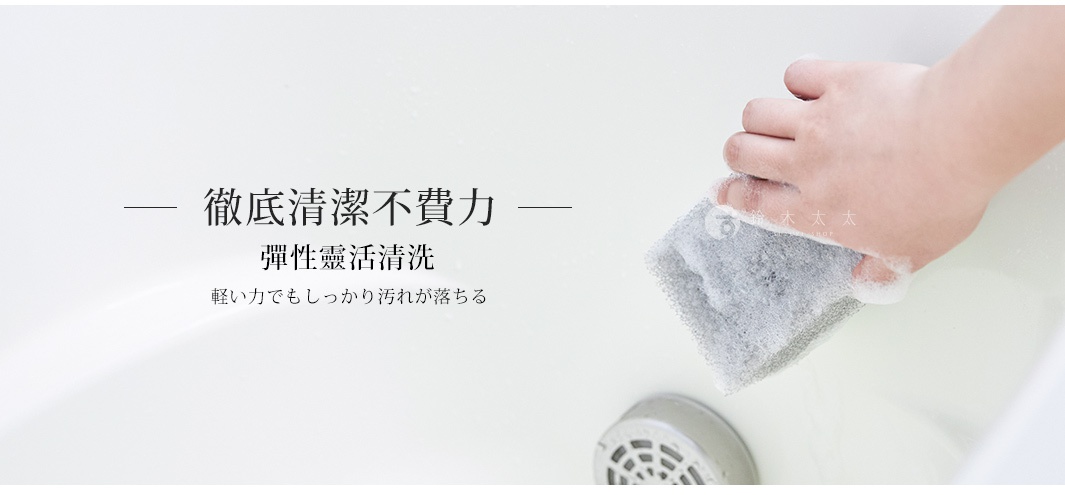 手持灰色海綿，沾滿白色泡沫，正在清潔白色浴缸表面。