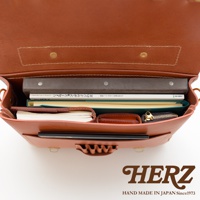 職人手作皮革傳統歐風三用學生包，棕色皮革，包內可見兩本書、筆記本、錢包和拉鍊小包，結構緊湊。