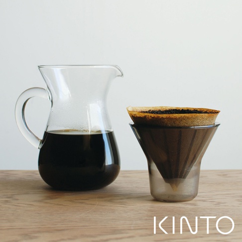 玻璃咖啡分享壺裝有深棕色咖啡，旁邊是裝有濾紙和咖啡渣的深灰色濾杯。