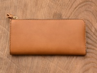 棕褐色皮革製成的L型長夾，配有雙拉鍊和金色拉鍊頭，皮革表面光滑，邊緣縫線整齊。