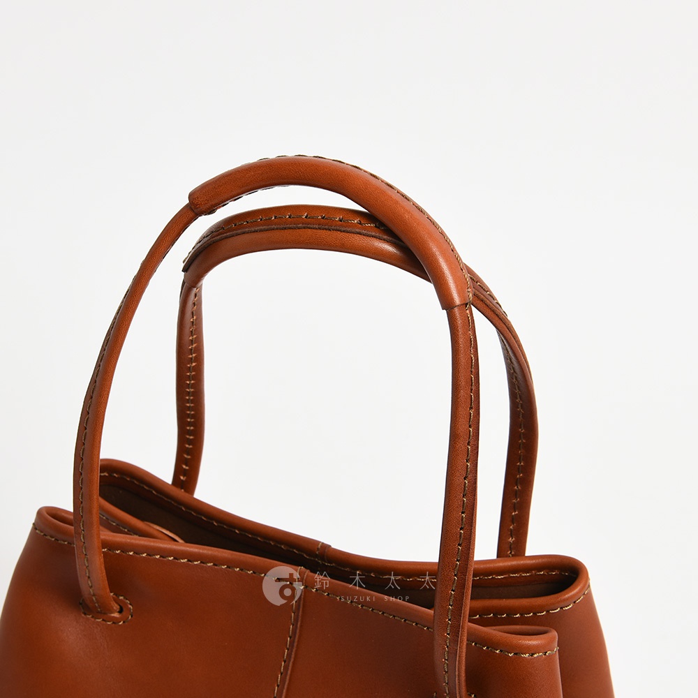 日本HERZ職人手作皮革托特包的棕色提把特寫，帶有精緻縫線細節