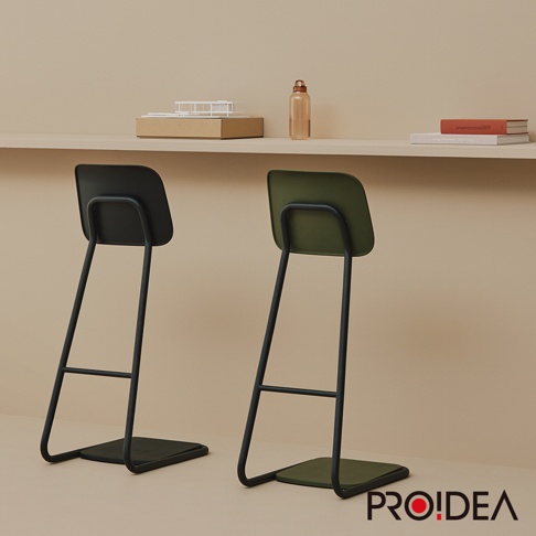 兩張STAN CHAIR人體工學站立椅，一張為黑色椅面與黑色椅架，另一張為軍綠色椅面與黑色椅架。椅面為簡潔的方形設計，椅架為金屬材質，呈現簡約線條。