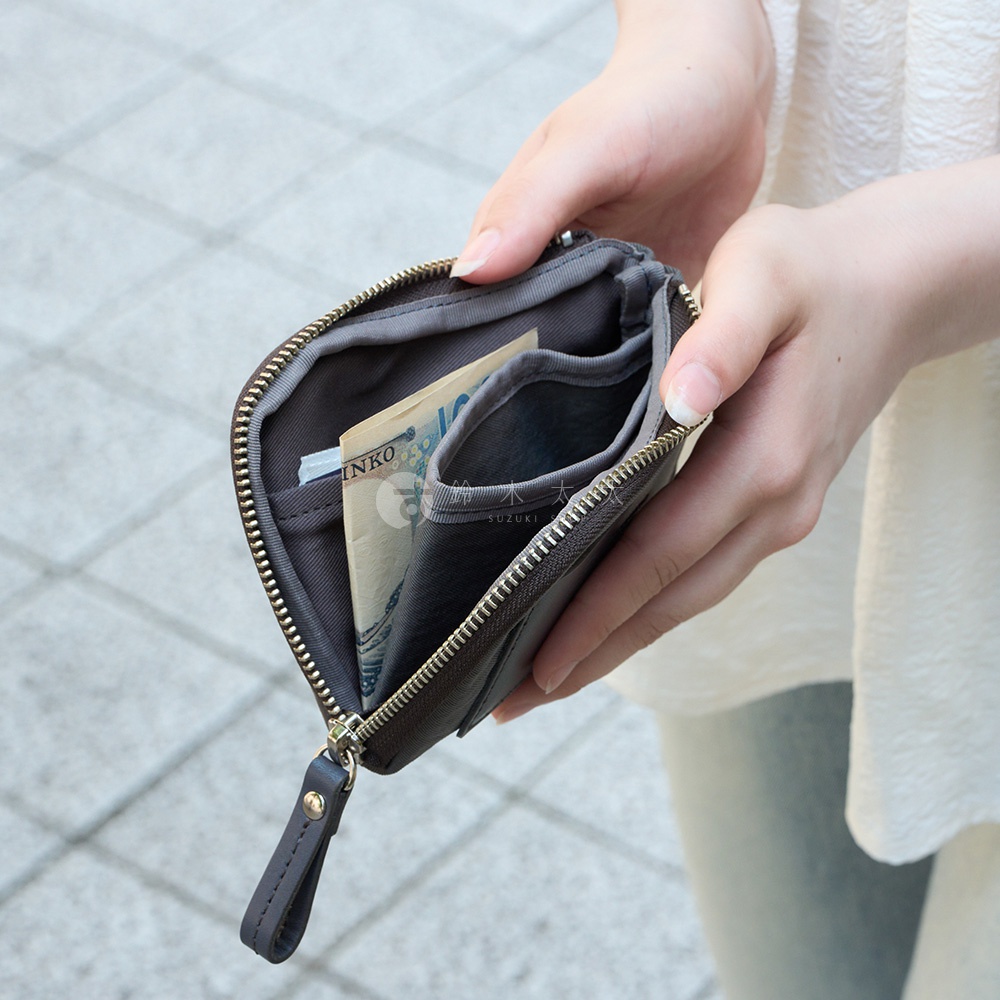 TUTUMU 防潑水迷你錢包，深棕色皮革材質，露出部分日圓紙鈔，方便拿取。