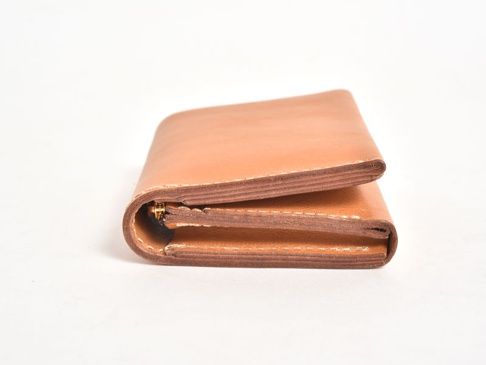 職人手作淺棕色皮革直式卡片收納雙折短夾，具有精緻縫線與金色拉鍊細節。