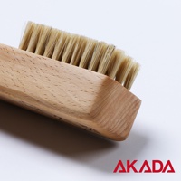 AKADA 品牌標誌，旁邊是一支木柄豬鬃刷，特寫鏡頭。