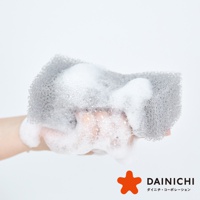 手握著帶有豐富泡沫的灰色網狀海綿，海綿表面呈現密集的小孔結構。