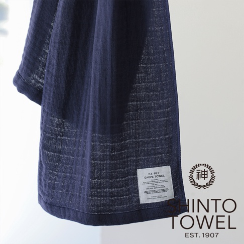 深藍色2.5層紗浴巾，材質輕薄透氣，織紋清晰，帶有品牌標籤。