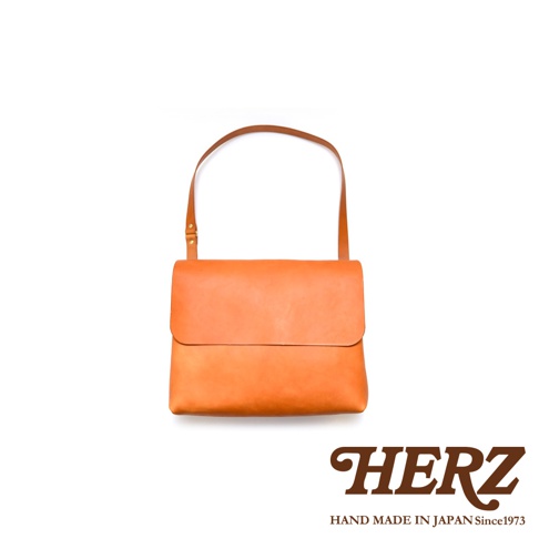 橘色皮革經典郵差包，翻蓋設計，可調整背帶，簡約實用，適合日常攜帶。