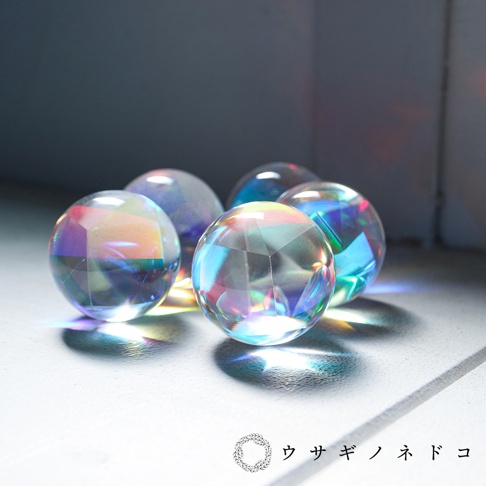 五顆透明的合光稜鏡球，表面有許多切割面，折射出彩虹般的光芒，散落在淺色背景上。