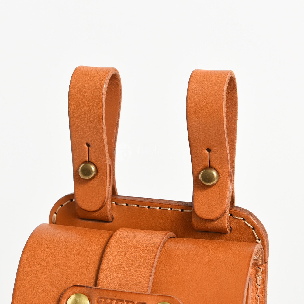 職人手作皮革經典腰袋，棕褐色皮革製成，兩條皮質掛繩以銅質卯釘固定，腰袋前方有皮帶穿過，展現簡約設計。