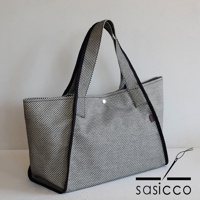 三河木綿刺子織可變形托特包，黑色與白色格紋圖案，配有黑色滾邊和提把，包身側面有品牌標籤。